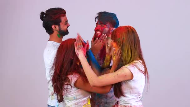 Cuatro estudiantes indios pintados en colores celebrando el festival holi en estudio blanco aislado fondo — Vídeos de Stock