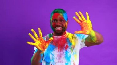 Afro-Amerikalı adam Holi festivalini Violet stüdyosunda kutluyor.