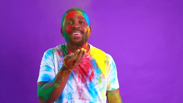 Afro americano hombre celebrar holi festival en violeta estudio fondo — Vídeo de stock