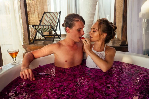 Um jovem casal juntos em um banho com pétalas e flores em um spa tropical — Fotografia de Stock