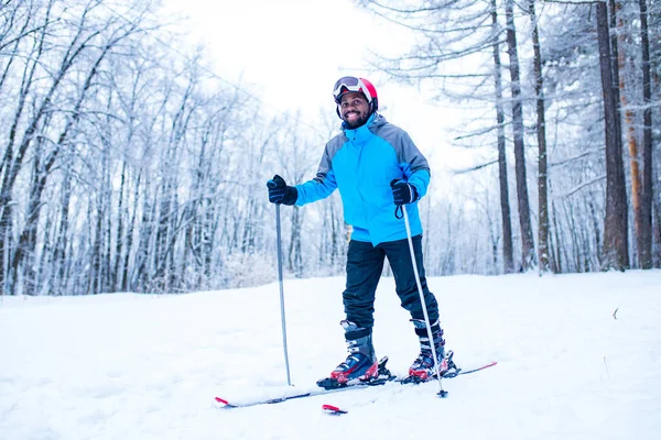 Afro americano uomo in giacca blu correre sci all'aperto nella foresta congelare — Foto Stock