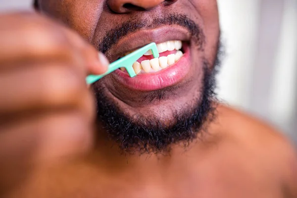 Hombre afroamericano limpiando sus dientes con hilo dental —  Fotos de Stock