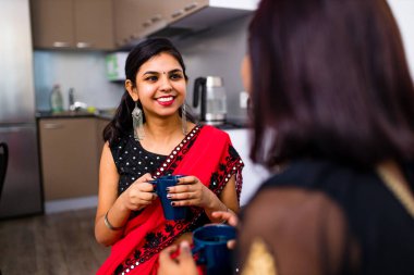 Masala çayını birlikte içen iki Hintli kadın.