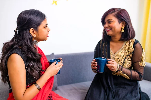 Две индийские женщины наслаждаются чаем масала вместе в гостиной — стоковое фото