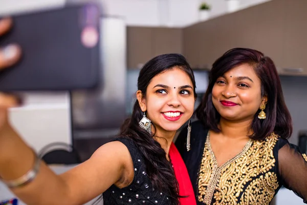 Две индийские женщины в Сари поговорить с семьей по телефону видео чата в гостиной в доме — стоковое фото