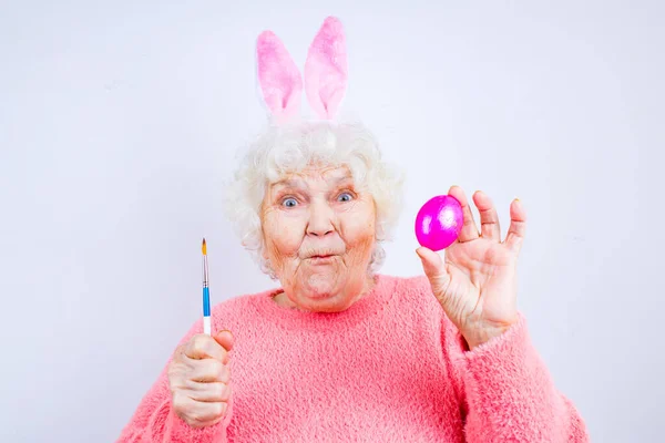 Glad 80-årig kvinna med kaninöron och påskägg — Stockfoto