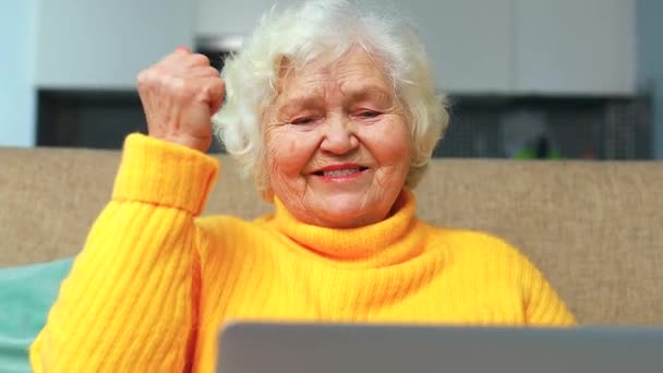W podeszłym wieku siwe włosy kobieta patrząc daleko siedzi w salonie — Wideo stockowe
