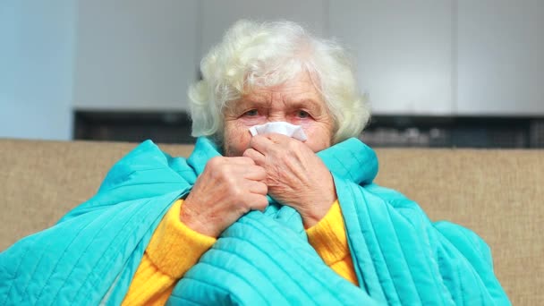 Old woman wrapped on blue blanked at home feel sick runny nose — Stock Video