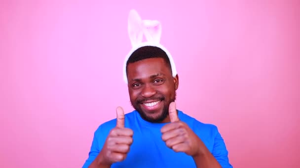 Счастливый молодой смельчак с ушами зайца на розовом фоне студии — стоковое видео