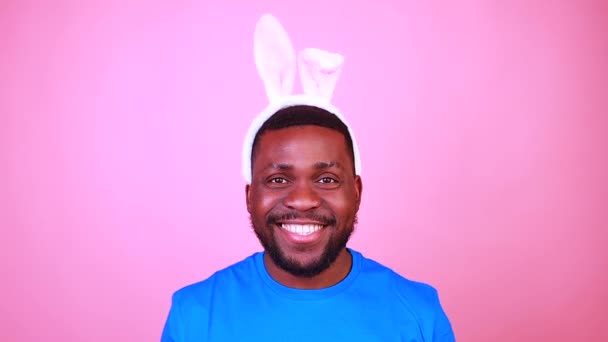 man wearing cute easter bunny ears in studio pink wall background