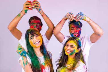 Dört mutlu arkadaş, beyaz arka plandaki stüdyoda geleneksel Holi zamanı geçiriyorlar.