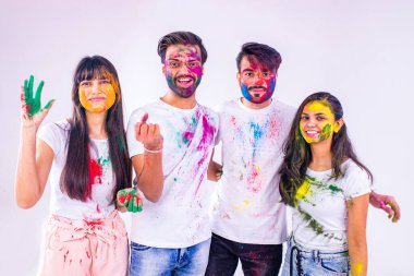 Stüdyo beyaz izole arka planda Holi festivalini renklerle boyayan dört Hintli öğrenci