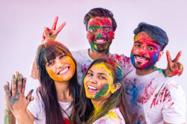 Stüdyo beyaz izole arka planda Holi festivalini renklerle boyayan dört Hintli öğrenci