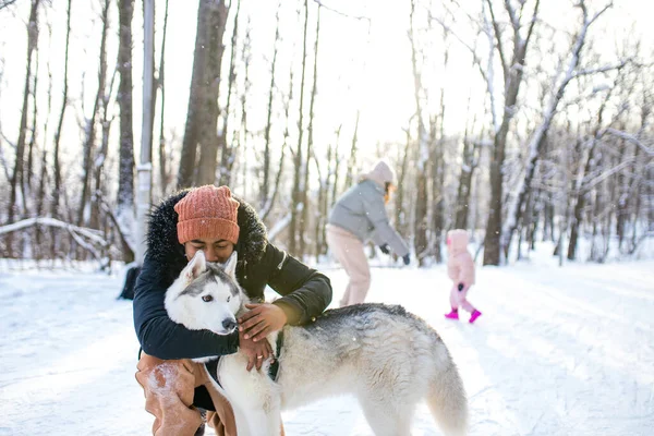 Mieszane wyścig człowiek przytulić jego pies husky w zimie Forest Park — Zdjęcie stockowe