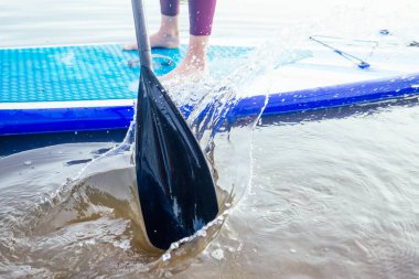 Durgun bir göl kıyısında ayakta durun, bacaklarınızı yakın tutun ve su sıçratın.