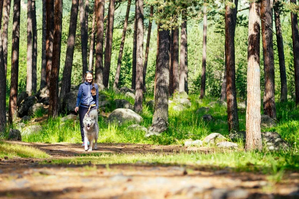 Jeune jolie fille courir en plein air au printemps avec chien de montagne — Photo