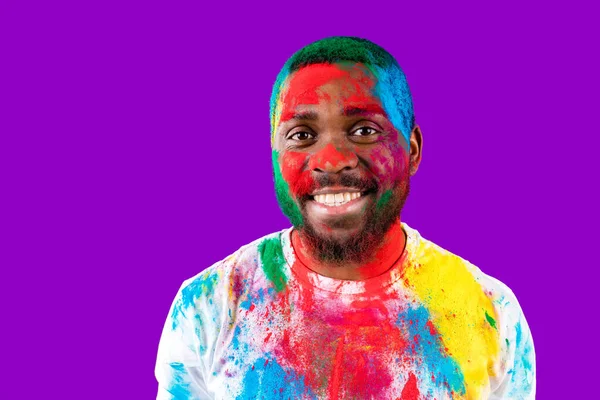 Afro americano homem celebrar holi festival em violeta estúdio fundo — Fotografia de Stock