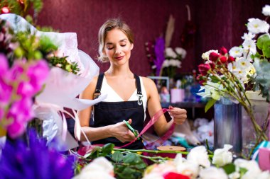 Çiçekçi bahar günü mağazada bir müşteri için buket yapıyor.