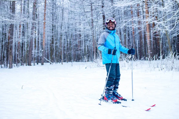 Afro americano uomo in giacca blu correre sci all'aperto nella foresta congelare — Foto Stock