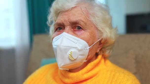 Старшая женщина носит маску для лица во время коронного вируса дома — стоковое видео