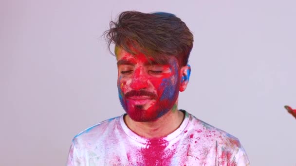 Hermoso indio estudiante hombre pintado en colores celebrando holi festival en estudio blanco aislado fondo — Vídeos de Stock
