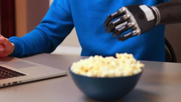 Genç adam dizüstü bilgisayarda film izliyor ve evde patlamış mısır yiyor. — Stok video
