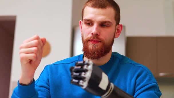 Молодий чоловік з сучасною біотехнологічною рукою в квартирі — стокове відео