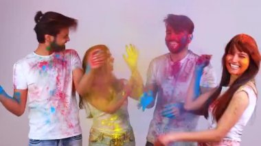 Dört mutlu arkadaş, beyaz arka plandaki stüdyoda geleneksel Holi zamanı geçiriyorlar.