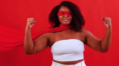 Kırmızı gözlü Latin kadın ve stüdyo arka planında uzun süper kahraman pelerini.