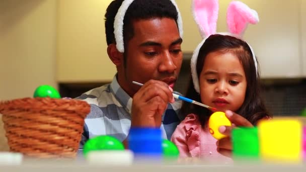 Szczęśliwa mieszana rodzina świętuje Wielkanoc, malując jajka pędzlem uśmiechając się i śmiejąc — Wideo stockowe
