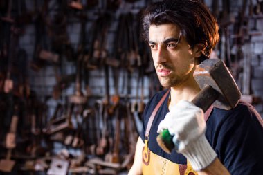 Otantik demirci, karanlık stüdyoda metal bir ürün üretiyor.