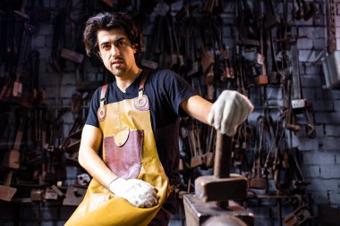 Otantik demirci, karanlık stüdyoda metal bir ürün üretiyor.