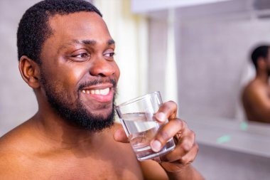 Aynanın yansıması, saf temiz maden suyu içen Afro-Amerikalı genç adama benziyor.