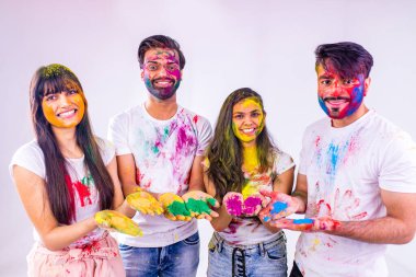 Dört mutlu arkadaş, beyaz arka plandaki stüdyoda geleneksel Holi zamanı geçiriyorlar.