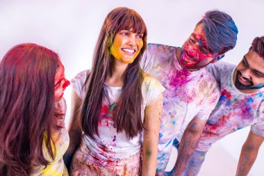 Stüdyo beyaz izole arka planda Holi festivalini renklerle boyayan dört Hintli öğrenci