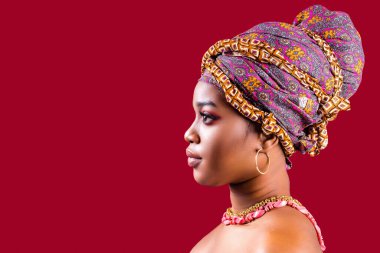 Kırmızı arka planda sarığa sarılı cazibeli koyu tenli kadın.