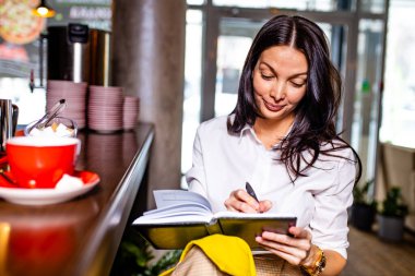 Masa başlığının yanında oturup çay içerken not defterinde Hintli notlar okuyordu.