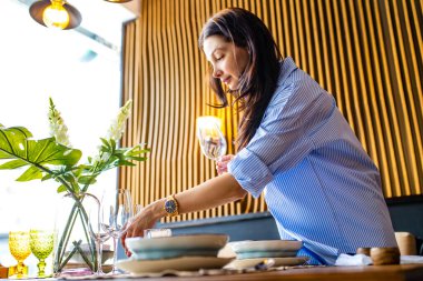 Genç ve güzel bir Hintli kadının portresi bulaşık yıkıyor ve masa gün ışığını ayarlıyor.