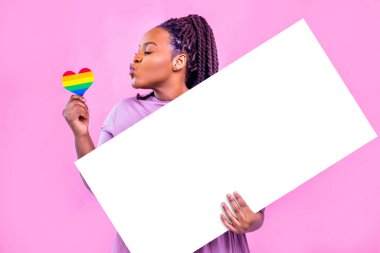 Latin İspanya boş bir pankart tutuyor Pembe stüdyoda gökkuşağı kalbini öpüyor