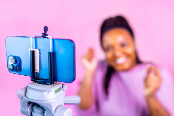 Saçları örgülü, sarı saçlı İspanyol kadın stüdyoda aboneleriyle telefonda konuşurken pembe elbise giyiyor.