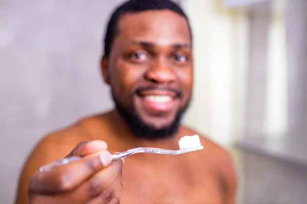 africa man toothbrush in bathroom looking at mirror