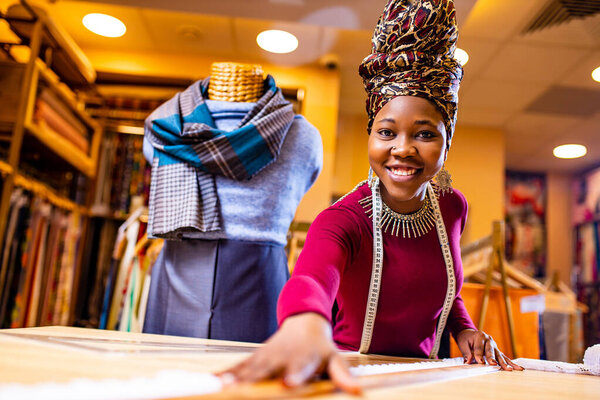 tanzanian woman with snake print turban over hear working in fabrics shop