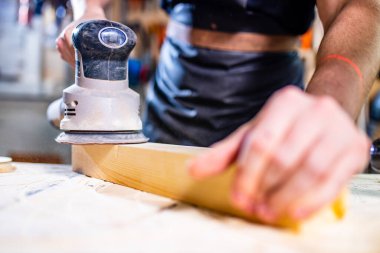 Genç marangoz testere testeresiyle tahta kesiyor.