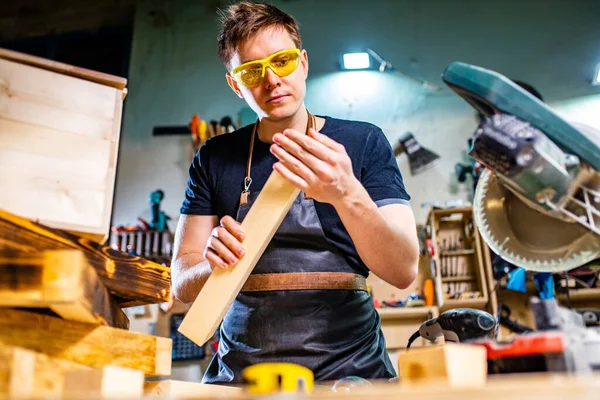 Portret van knappe timmerman werkend met plank in werkplaats — Stockfoto