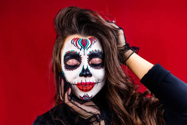 Mujer joven mexicana en un traje de Calavera Catrina sobre fondo de estudio rojo —  Fotos de Stock