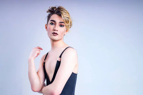 Lüks sarı saçlı ve beyaz duvarlı muhteşem makyajlı Asyalı bir adam. Arka plan tutkusu. Kameraya bak.