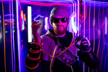 Protez modern eli olan oyuncu erkek. Sağ elini tel lamba duvarına sarmış.