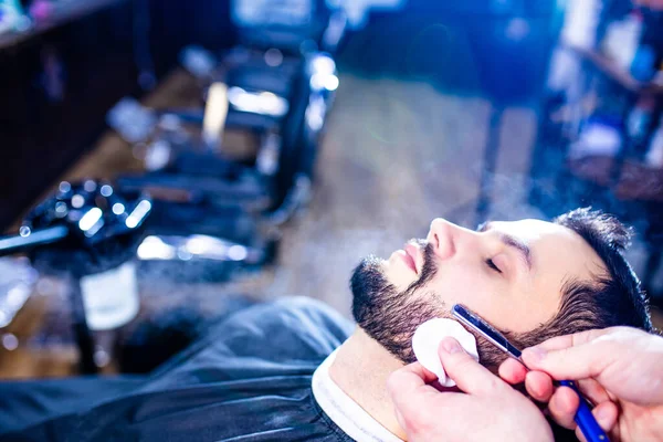 Arap yakışıklı sakallı adam berber dükkanında saçını kestiriyor.