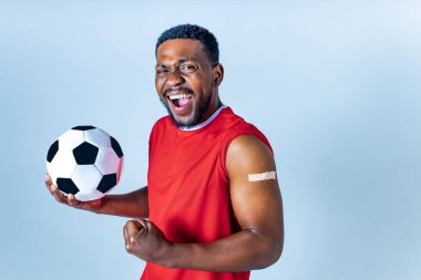 Stüdyoda aşı olduktan sonra kolunu gösteren Afro-Amerikan sporcu.