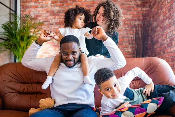 afro american mixed-raced family looking at camera in cozy summer day light in living room